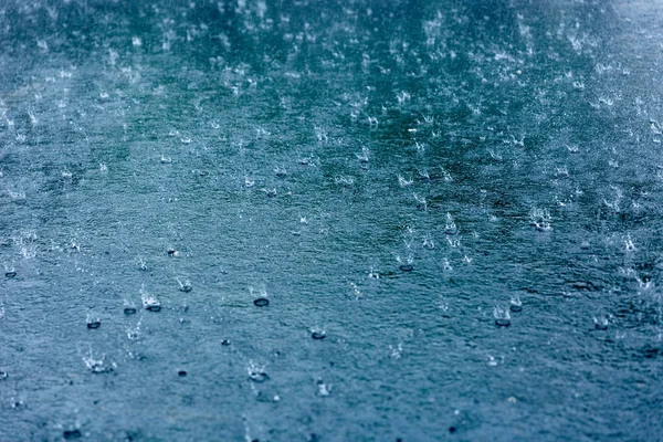 Gotas de chuva ondulando em uma poça com reflexão céu azul — Fotografia de Stock