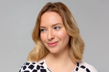 Tek renkli arka planda kameraya bakıp gülümseyen güzel kızın portresi..