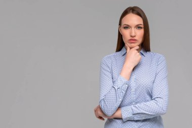 Küstah ve başarılı görünümlü kadın blogcu çenesinin altında yumruklar tutuyor ve yüzsüz bir sırıtışla kameraya bakıyor. Diş telli kız.