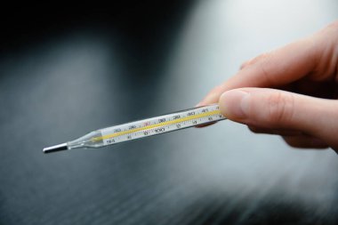 Koronavirüs belirtileri. Ateşli ve baş ağrısı çeken kadın elleri termometreyi tutuyor. çok yüksek sıcaklık.