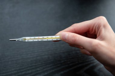 Koronavirüs belirtileri. Ateşli ve baş ağrısı çeken kadın elleri termometreyi tutuyor. çok yüksek sıcaklık.