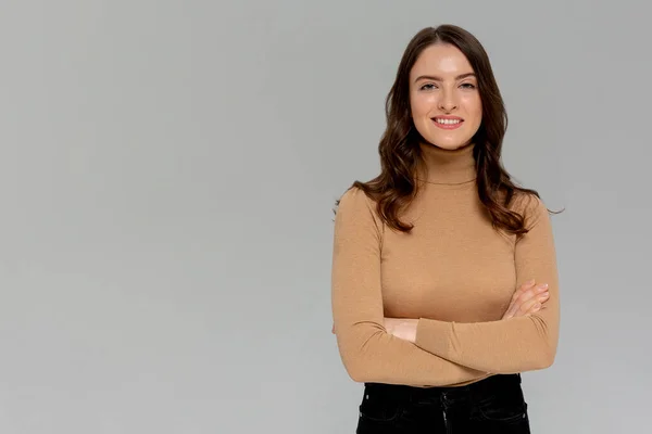 Çekici, kendine güvenen, yaratıcı, güzel görünümlü, patronluk taslayan, kollarını kavuşturan, kendine güvenen, gülümseyen, kendine güvenen, hedeflerine ulaşan, şanslı, tek renkli arka plan sahibi bir kadın.