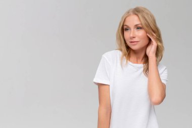 Portrait shot of beautiful young woman daydreaming while sitting at isolated white background.