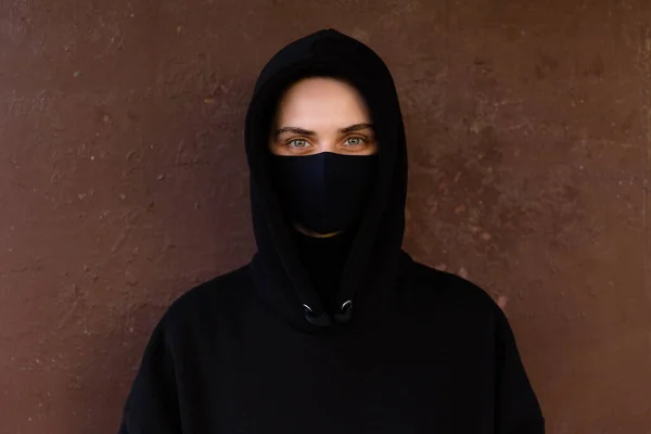 Young woman wearing face mask. Handsome woman in black hoodie wear black medical mask. Pandemic coronavirus covid-19 quarantine period concept.
