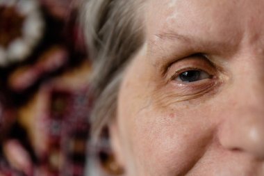 Hüzün dolu yorgun bakışlarla emekli bir kadın başka tarafa bakıyor, aşırı yakın çekim.