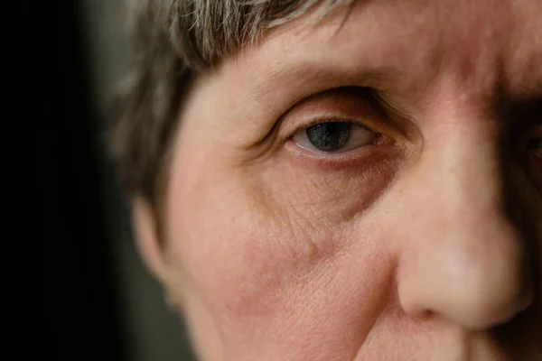 Retired woman with tired glance full of sadness looking away, extreme close-up shot