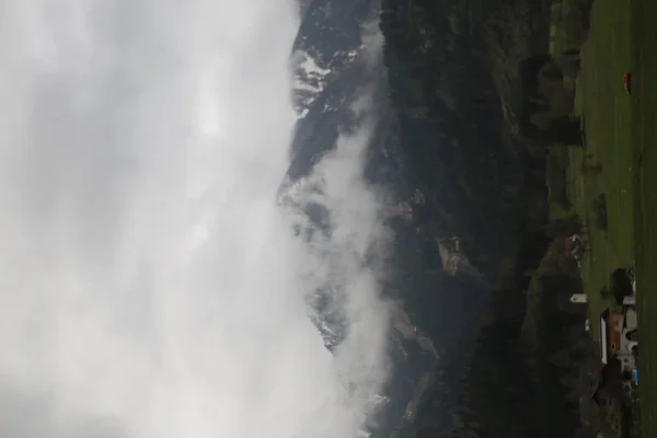 Mistige wolken stijgen van donkere alpine bergbos — Stockfoto