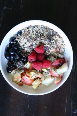 karışık meyve ve kahverengi ahşap masa üzerinde beyaz bir kase mısır gevreği