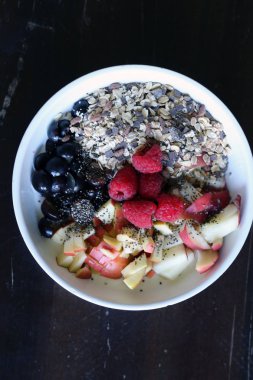 karışık meyve ve kahverengi ahşap masa üzerinde beyaz bir kase mısır gevreği