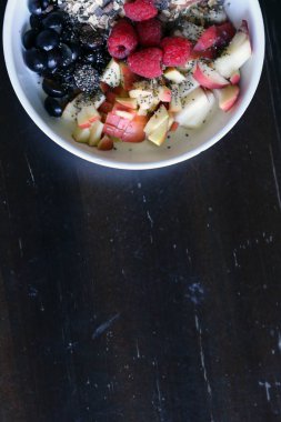 karışık meyve ve kahverengi ahşap masa üzerinde beyaz bir kase mısır gevreği