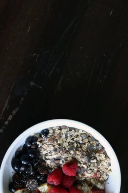 karışık meyve ve kahverengi ahşap masa üzerinde beyaz bir kase mısır gevreği