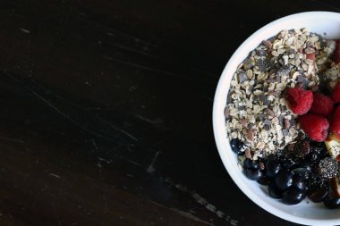 karışık meyve ve kahverengi ahşap masa üzerinde beyaz bir kase mısır gevreği