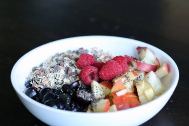 karışık meyve ve kahverengi ahşap masa üzerinde beyaz bir kase mısır gevreği