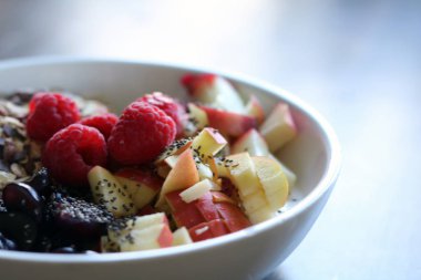 karışık meyve ve kahverengi ahşap masa üzerinde beyaz bir kase mısır gevreği