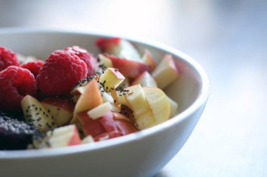 karışık meyve ve kahverengi ahşap masa üzerinde beyaz bir kase mısır gevreği