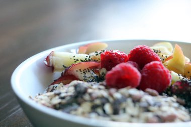 karışık meyve ve kahverengi ahşap masa üzerinde beyaz bir kase mısır gevreği