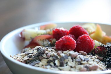 karışık meyve ve kahverengi ahşap masa üzerinde beyaz bir kase mısır gevreği