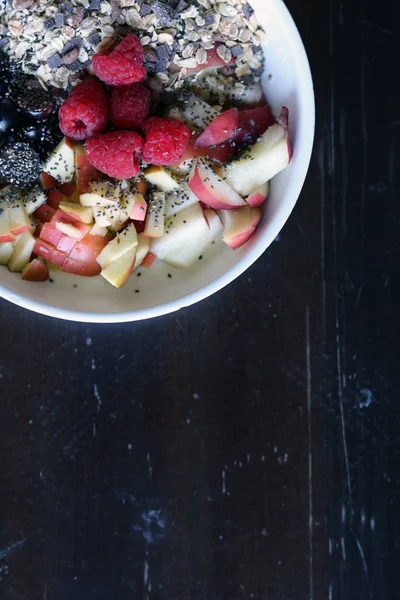 Fruta mezclada y cereal en un tazón blanco sobre mesa de madera marrón — Foto de Stock