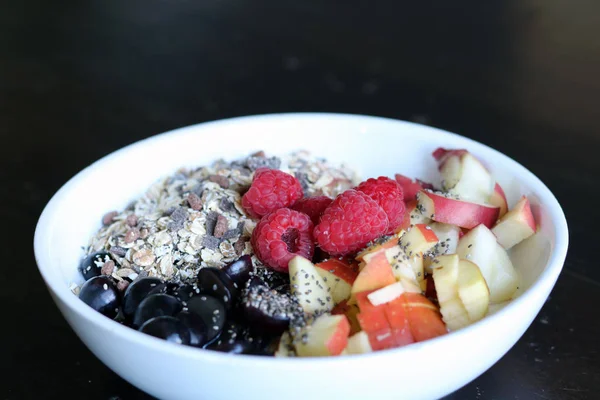 karışık meyve ve kahverengi ahşap masa üzerinde beyaz bir kase mısır gevreği