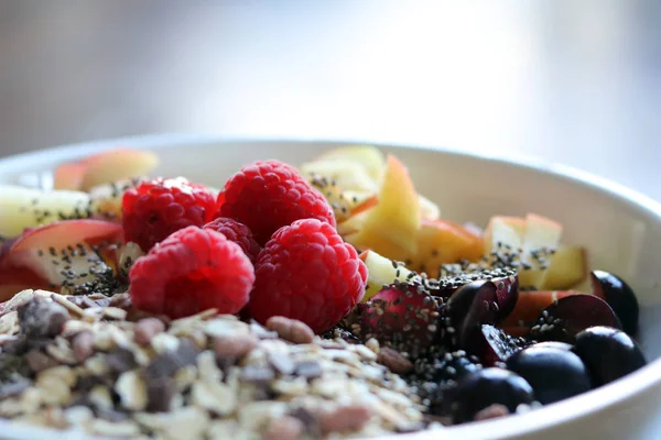 Gemischtes Obst und Müsli in einer weißen Schüssel auf einem braunen Holztisch — Stockfoto