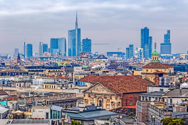MILAN, ITALY - DECEMBER 11, 2016: View over Milan from the top of the gothic cathedral Duomo di Milano (Milan Cathedral), Italy. Roof in the foreground, skyscrapers of the city in the background.