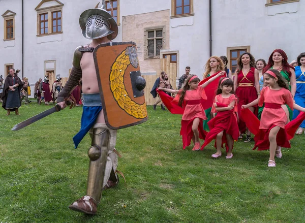 Gladiatore romano in costume da battaglia e un gruppo di giovani gir romano — Foto Stock