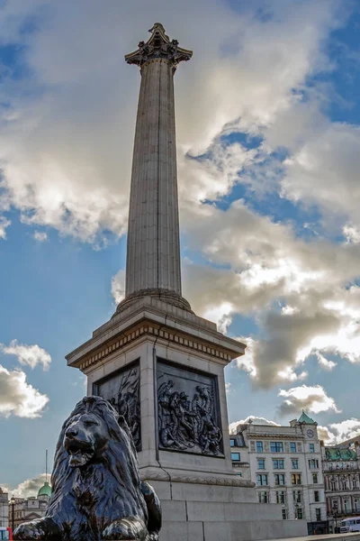 Estatua de un león y columna de Nelson en Trafalgar Square, Londres — Foto de Stock