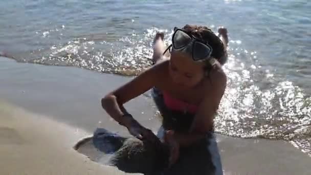Denizin kenarında kumda oynayan küçük kız — Stok video