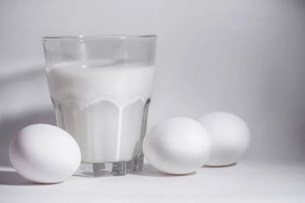 Latte in un vaso di vetro e uova — Foto Stock