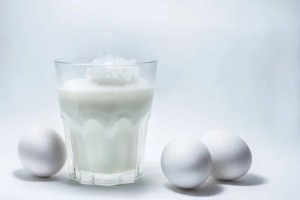 Latte in un vaso di vetro e uova — Foto Stock