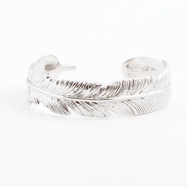 Luxurious slim beautiful silver bracelet in the form of a feather on a gray background — Stock Photo, Image