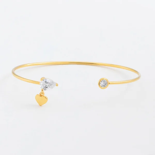 Luxueux bracelet mince en or avec des pierres et des cristaux avec des gouttes sur un fond gris — Photo