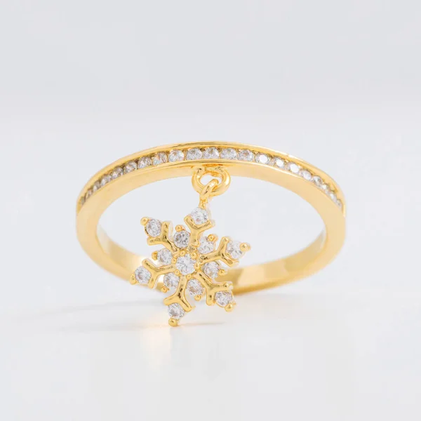 Luxueuse bague bijoux en or avec cristaux et strass, avec un flocon de neige décoratif sur un fond gris — Photo