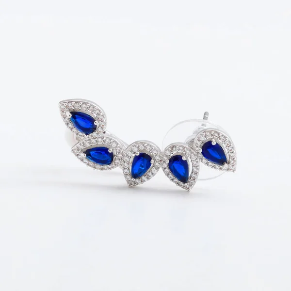 Piękne luksusowe światło błyszczące spinki srebrny kolczyk, z niebieskie kryształy, krople, na szarym tle — Zdjęcie stockowe