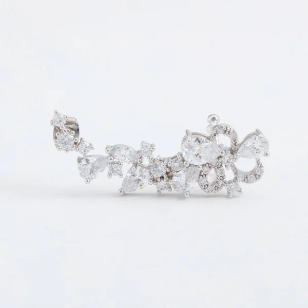 Luxuriöse schöne leicht glänzende silberne Manschettenohrring, mit Kristallen, auf einem grauen Hintergrund — Stockfoto