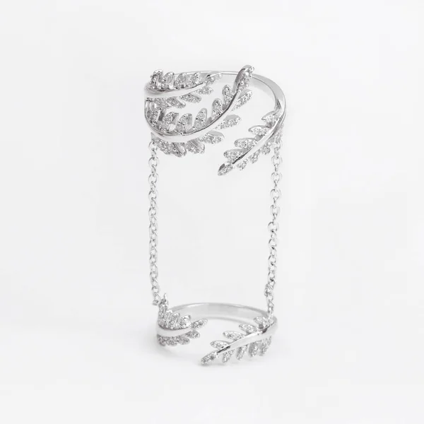 Luxury beautiful light silver double ring with chains and crystals leaves on a gray background — Stock Photo, Image