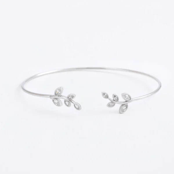 Lussuoso sottile bellissimo braccialetto d'argento con foglie e pietre e cristalli su uno sfondo grigio — Foto Stock