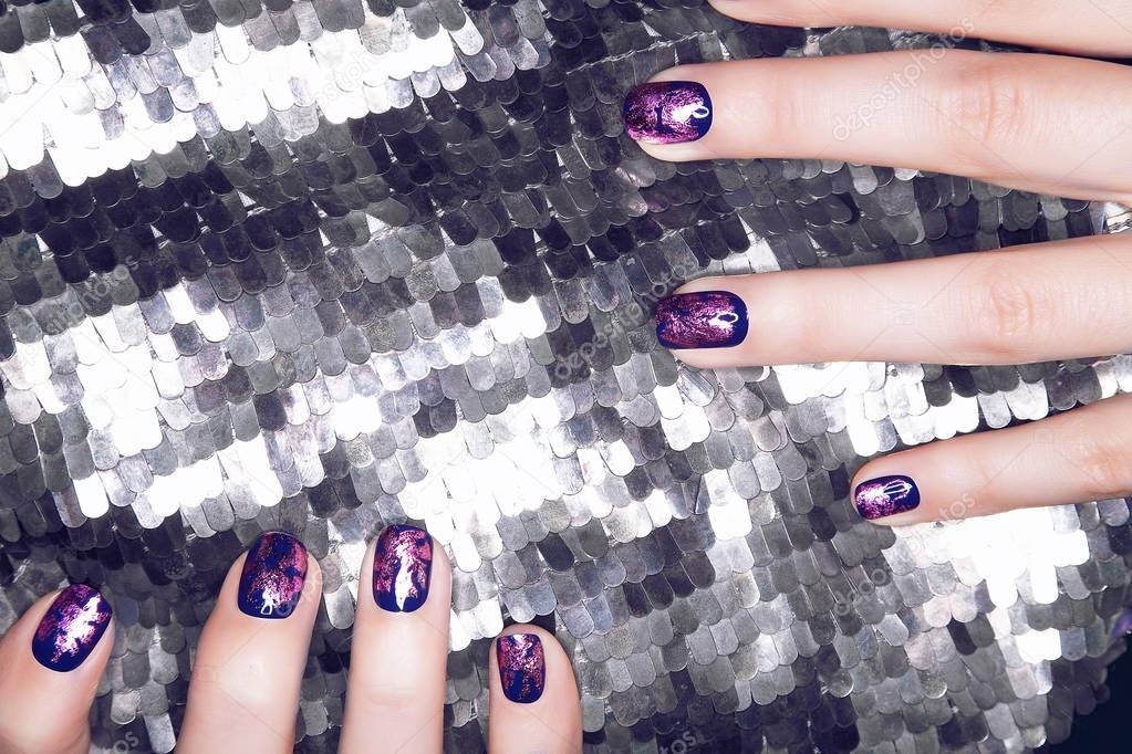Closeup of hands with purple manicure on nails, silver