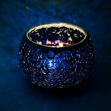 Mavi cam içinde parlayan bir mum ışık ışınları ile bir güzel şamdan top