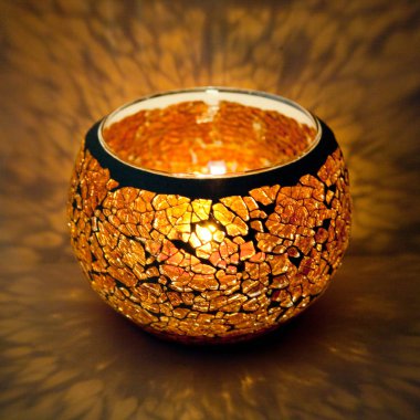 Turuncu cam içinde parlayan bir mum ışık ışınları ile bir güzel şamdan top