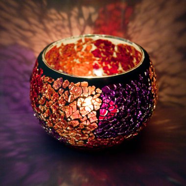 Turuncu ve mor cam içinde parlayan bir mum ışık ışınları ile bir güzel şamdan top