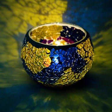 Sarı ve mavi cam içinde parlayan bir mum ışık ışınları ile bir güzel şamdan top