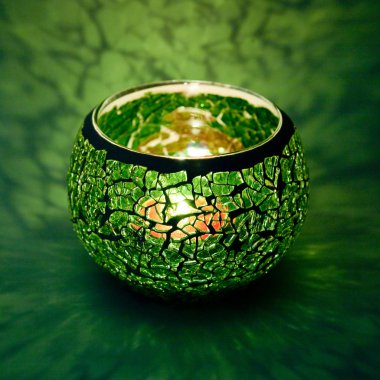 Yeşil cam içinde parlayan bir mum ışık ışınları ile bir güzel şamdan top