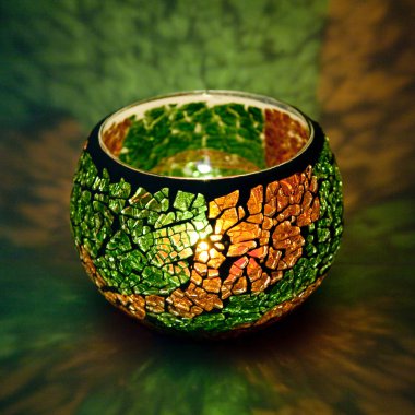 İçinde parlayan bir mum ışık ışınları bir güzel şamdan topla portakal ve yeşil cam