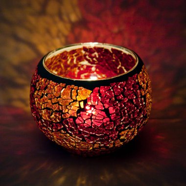 Turuncu ve pembe cam içinde parlayan bir mum ışık ışınları ile bir güzel şamdan top