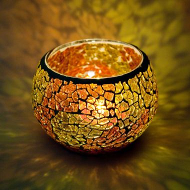 Turuncu ve sarı renkli cam içinde parlayan bir mum ışık ışınları ile bir güzel şamdan top