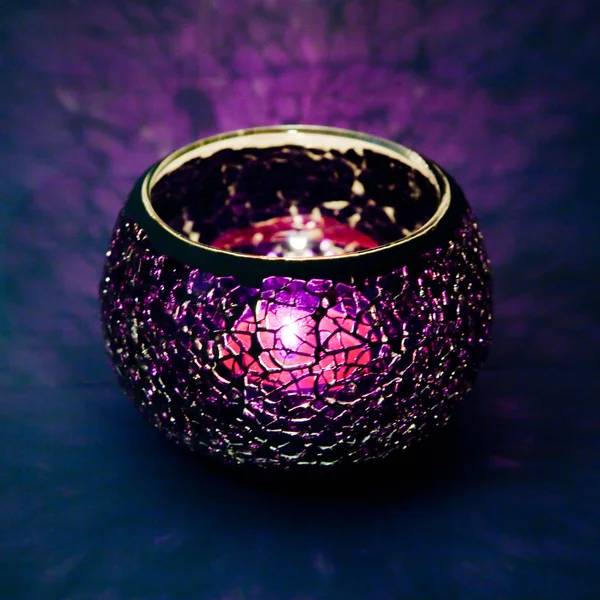 Menekşe cam içinde parlayan bir mum ışık ışınları ile bir güzel şamdan top