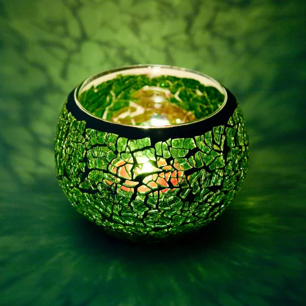 Yeşil cam içinde parlayan bir mum ışık ışınları ile bir güzel şamdan top