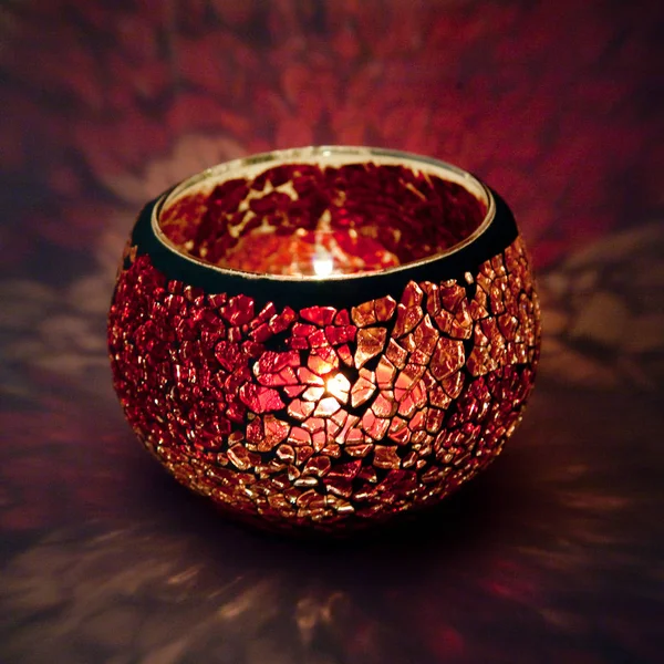 Kırmızı ve pembe cam içinde parlayan bir mum ışık ışınları ile bir güzel şamdan top