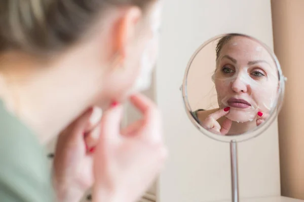 Cosmetic face mask and girl look in the mirror